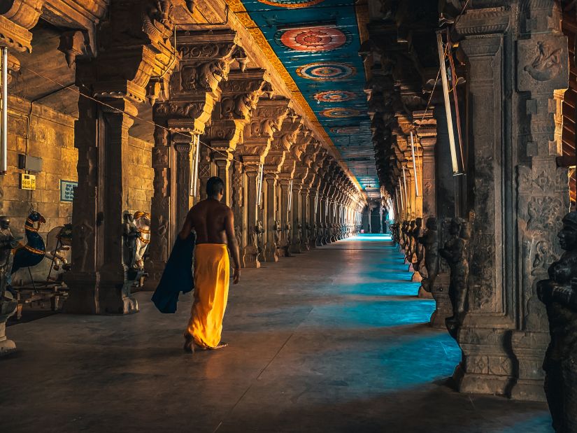 a woman walking inside a temple that has many beams