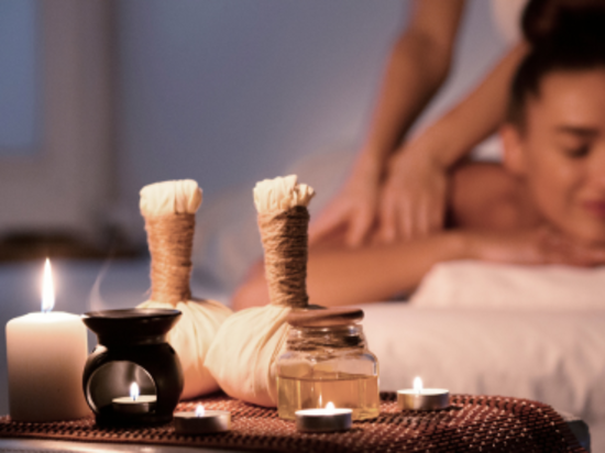 Spa setting with massage tools, candles, and a treatment in progress.