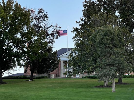 A building tucked away behind trees with the flag of the US