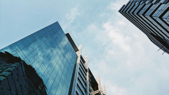 Looking up from the base of skyscrapers, reflecting clouds on their glass facades