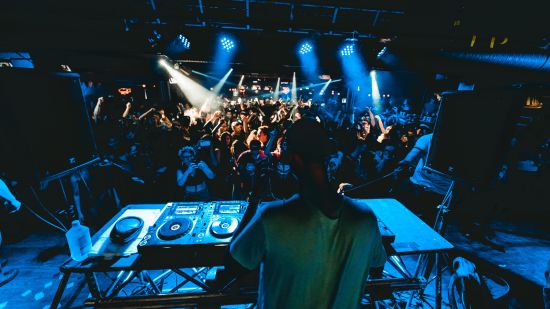 A DJ plays music as the crowd dances - Nightlife in South Goa