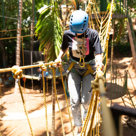 A person crossing a Burma Bridge - Stone Wood Nature Resort, Gokarna