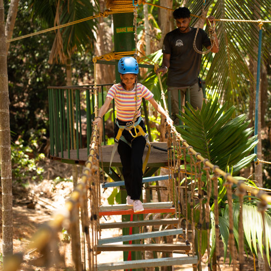 A person navigating a Quake Bridge during a hot sunny day - Stone Wood Nature Resort, Gokarna