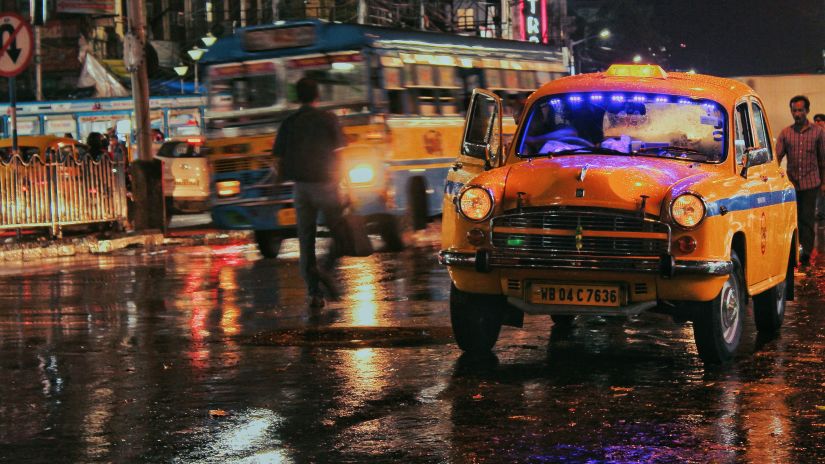 a yellow taxi driving in the rain on a wet road