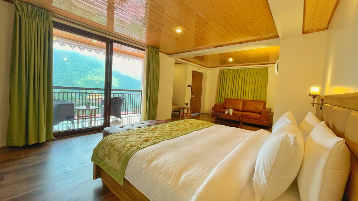 A room consisting of a clean bed, a side table lamp, a sofa, a coffee table, green curtains and a balcony -  Voyage Songfum Resort & Spa