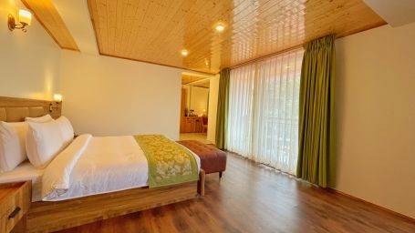 A beautifully decorated wooden bed, side drawer, green curitains, tea and coffee maker - Voyage Songfum Resort & Spa