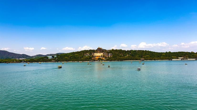 a palace in the middle of a hill near a lake with blue skies in the background