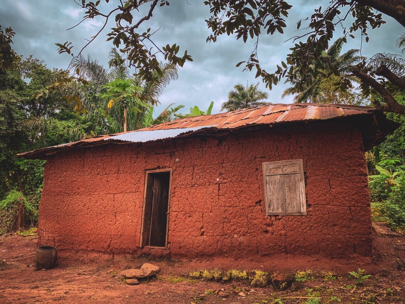 A mud house with greenery in the background