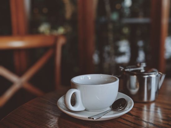 Image of a white coloured cup in focus kept on a wooden table - Stone Wood Mountain Resort, Dharamshala