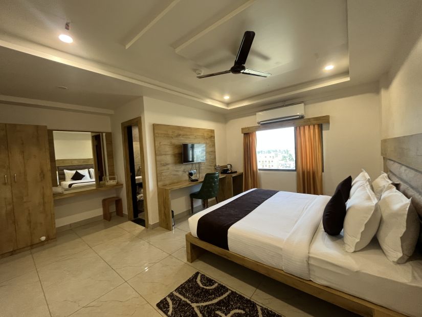 Side view of the Executive room with a cosy bed and a television mounted on the wall at Clarks Collection, Somnath