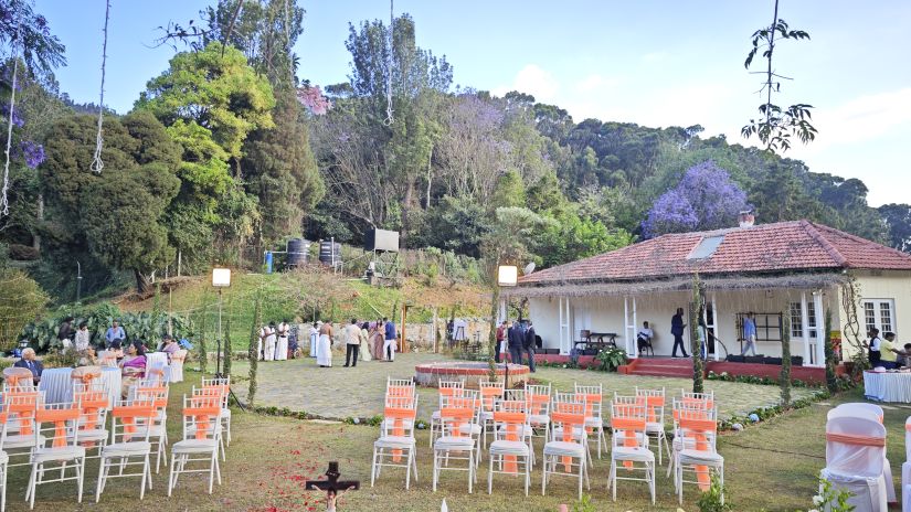 Wedding setup in Coonoor with rows of chairs and a central water feature under a tree adorned with purple flowers.