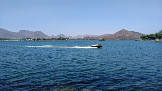 fast moving speedboat in udaipur lake amidst the majestic mountains