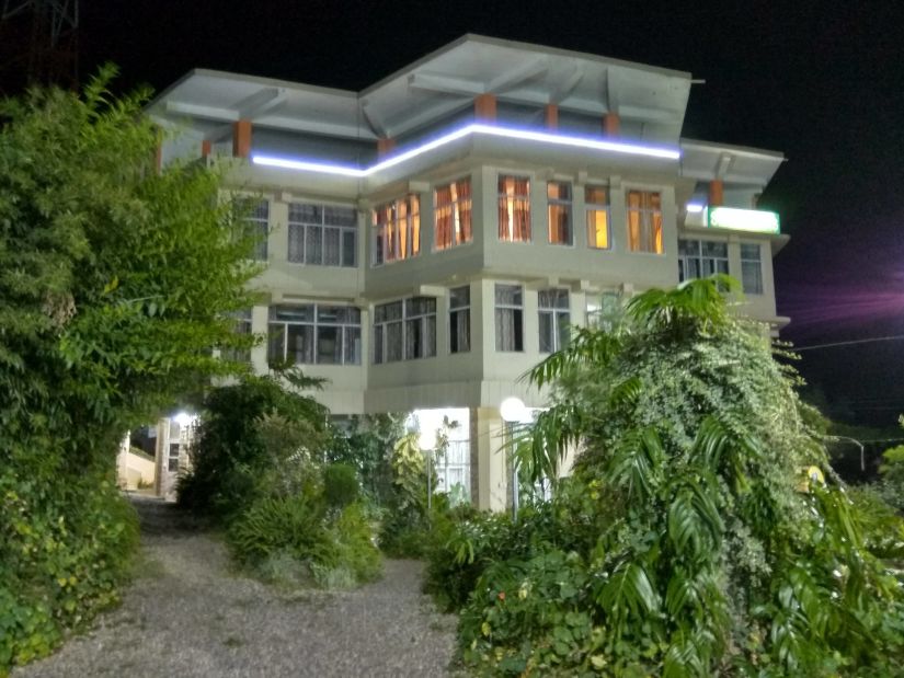 exterior of a hotel building that is shot from a lower angle that has green trees near entrance - Little Mastiff Silver Oaks, Palampur