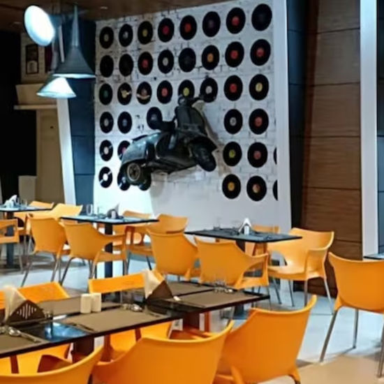 Close-up of the hotel dining area showing orange chairs and a feature wall with a scooter artwork.