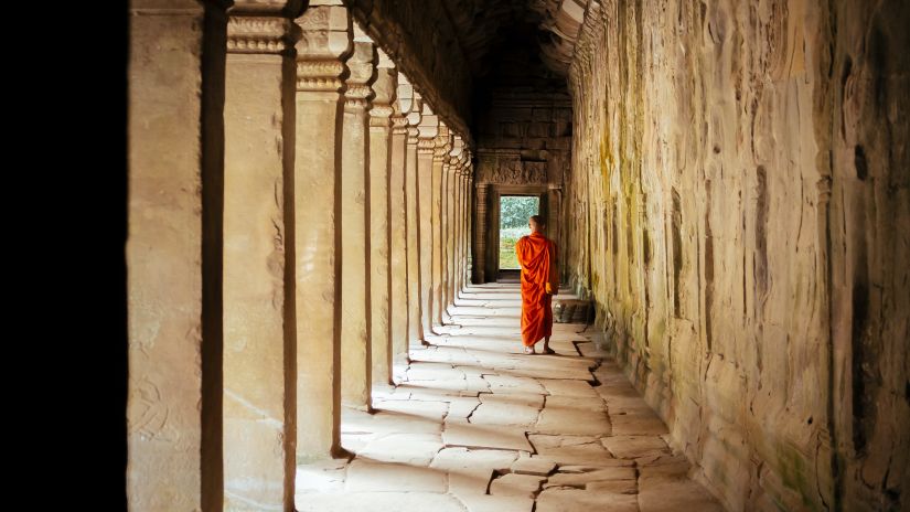 A stone passage and pillar with a person walking.