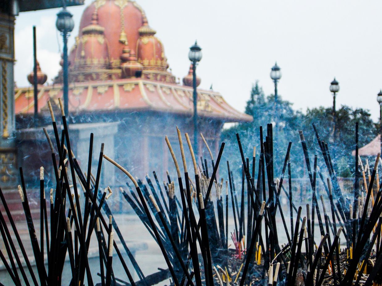 Image of incense sticks that are burning with the a glimpse of the temple in the background