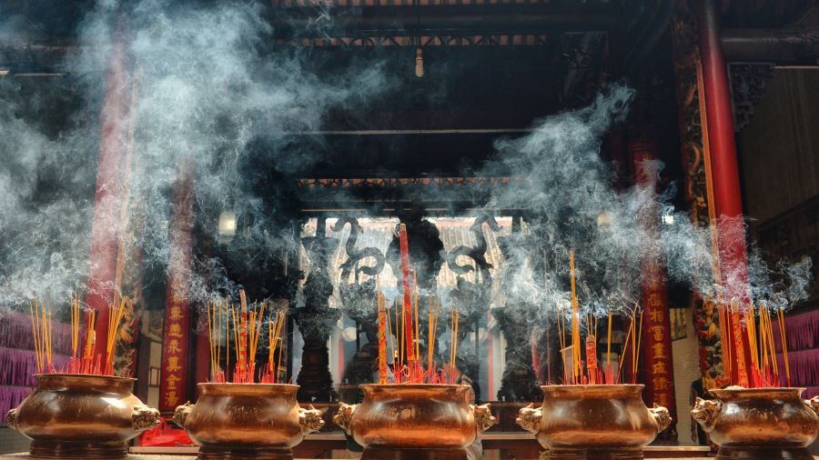 lit incense sticks kept in five pots in front of a temple