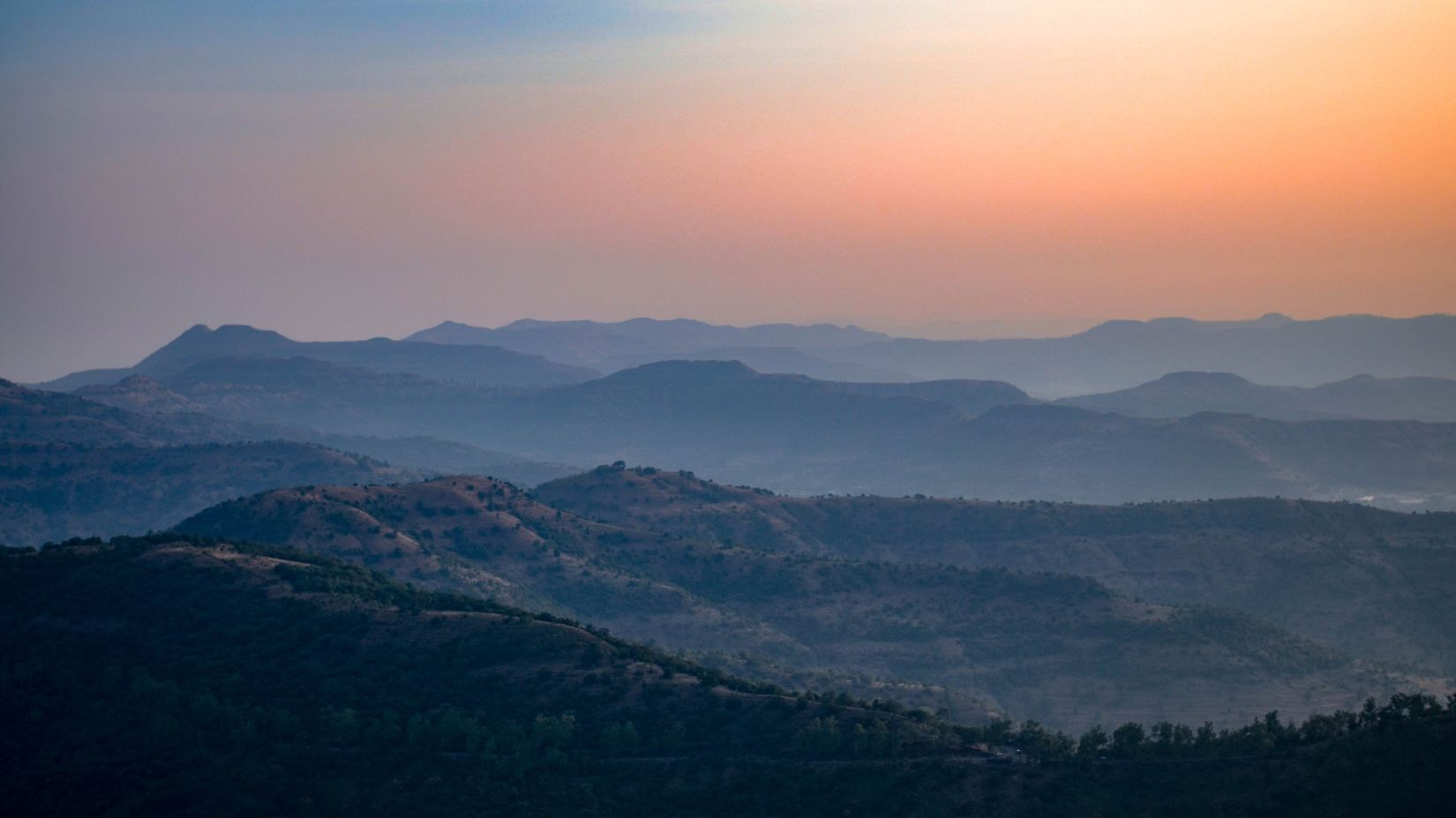 Forest covered mountains with pink sky