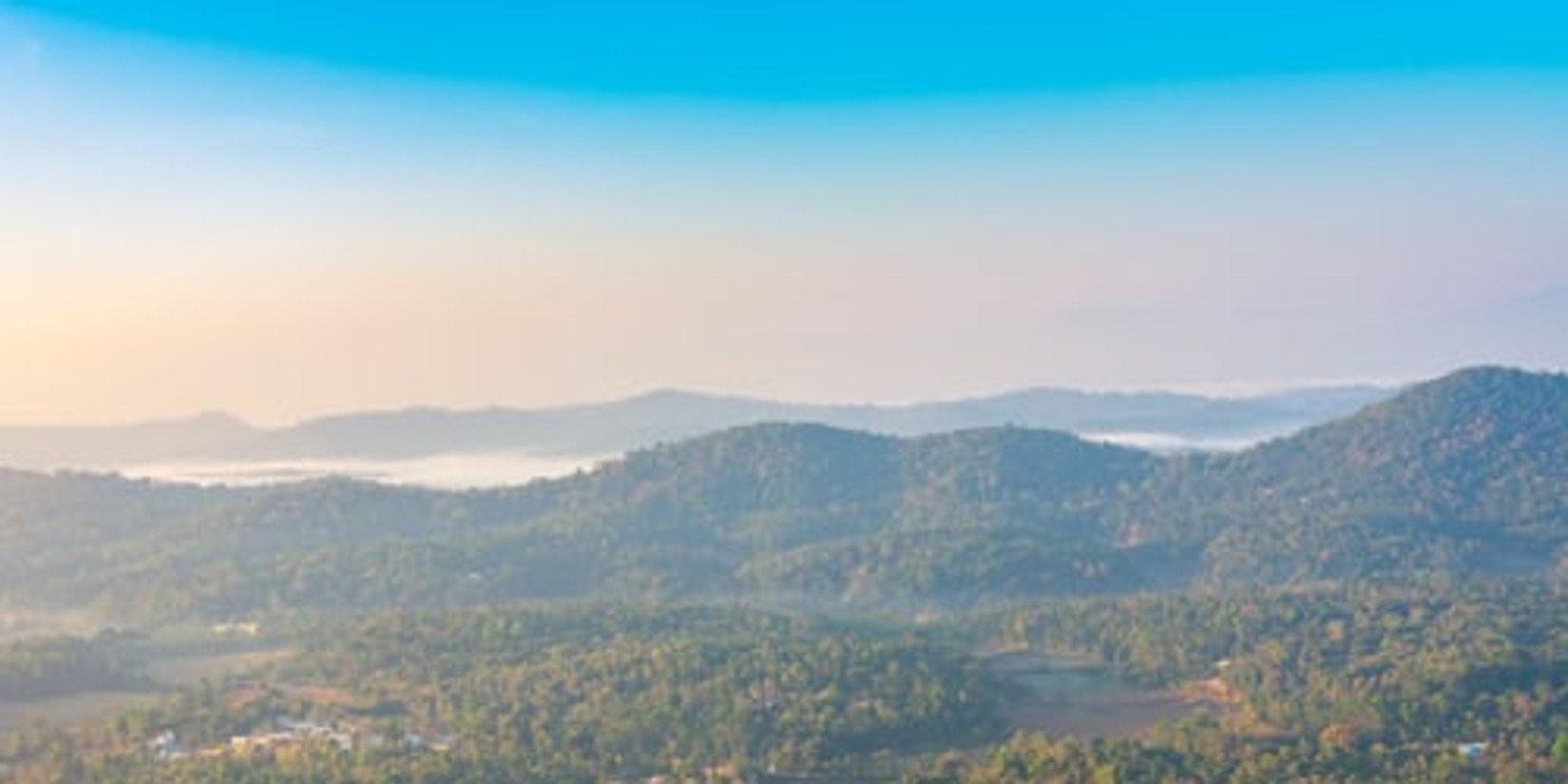 Misty hills with forest and a clear sky.