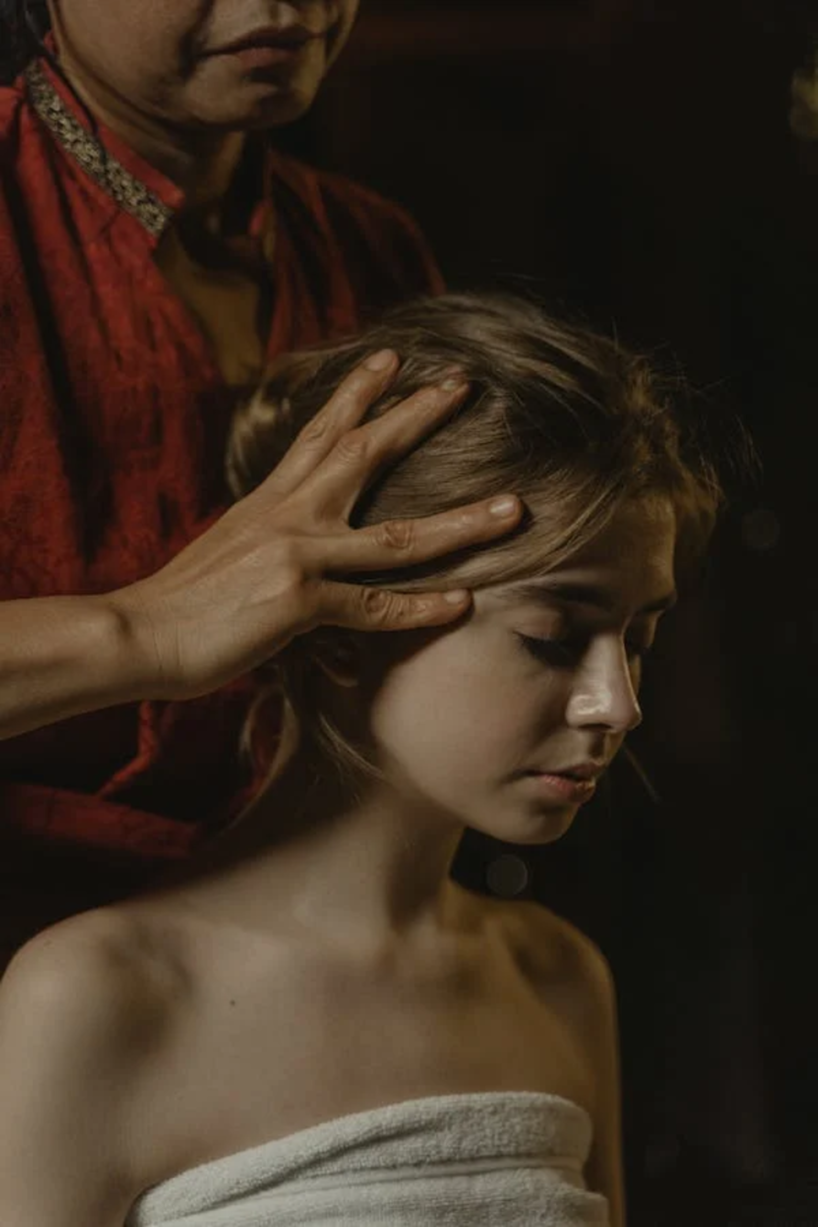 A dark, moody photograph of a head massage in progress, conveying a deep sense of relaxation and indulgence..