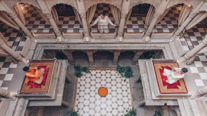 an image of a palace decked with white tiles with a lady standing by a pillar