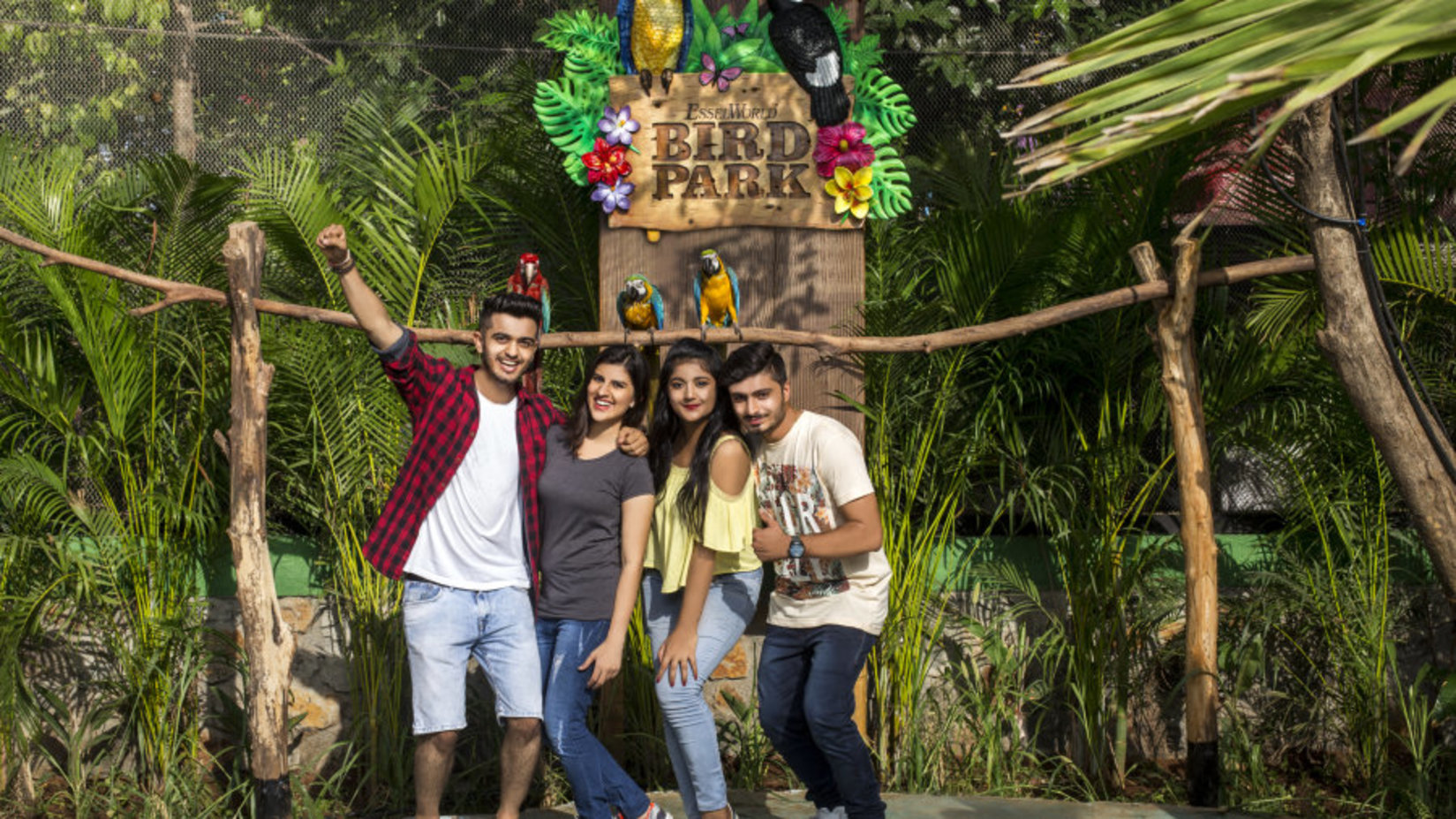 4 people posing in front of the Bird Park logo with a topical background