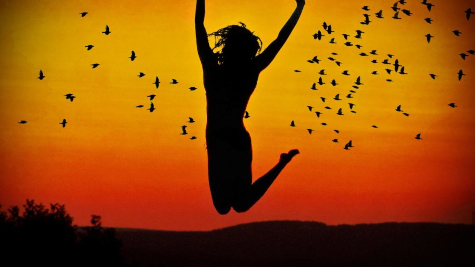 Woman jumping in the air with the evening sky in the background