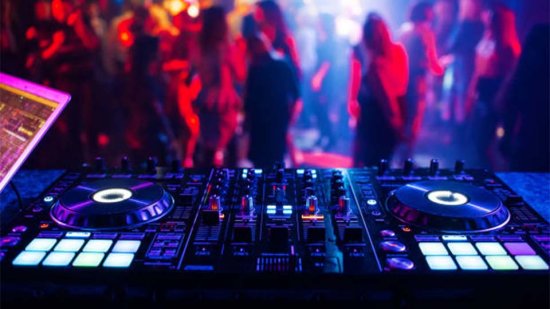 A dj desk with vinyl records and people dancing in the background