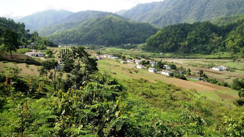 Few building surrounded by lush greenery and mountains in the background