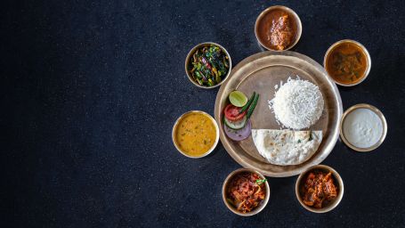 an indian food thali with a variety of curries and rice