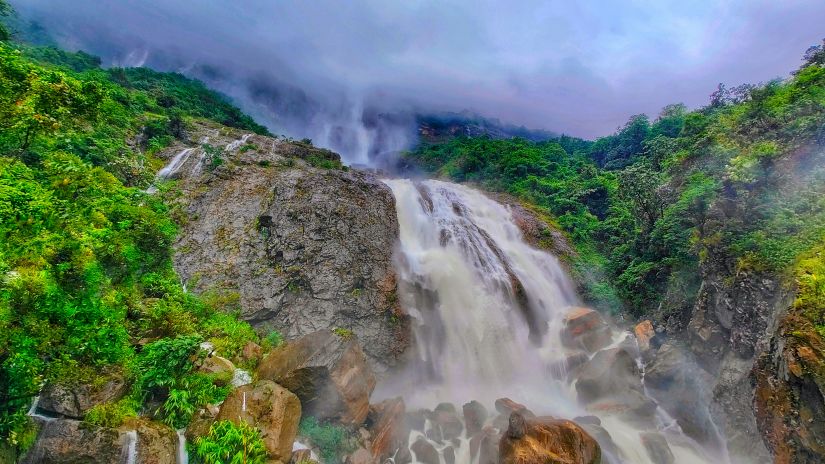 an overview of Kynrem Falls with tree cover on either sides and dark clouds in the background