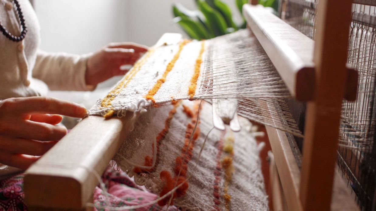 a person knitting cotton in a loom