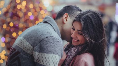 a man kissing a neck of a woman and the woman smiling