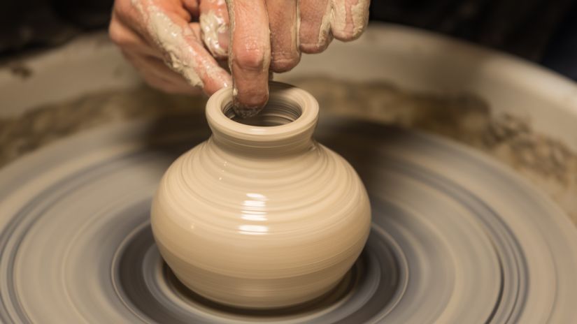 Moulding wet clay into a pot