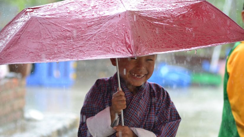 A small child holding an umbrella during monsoon