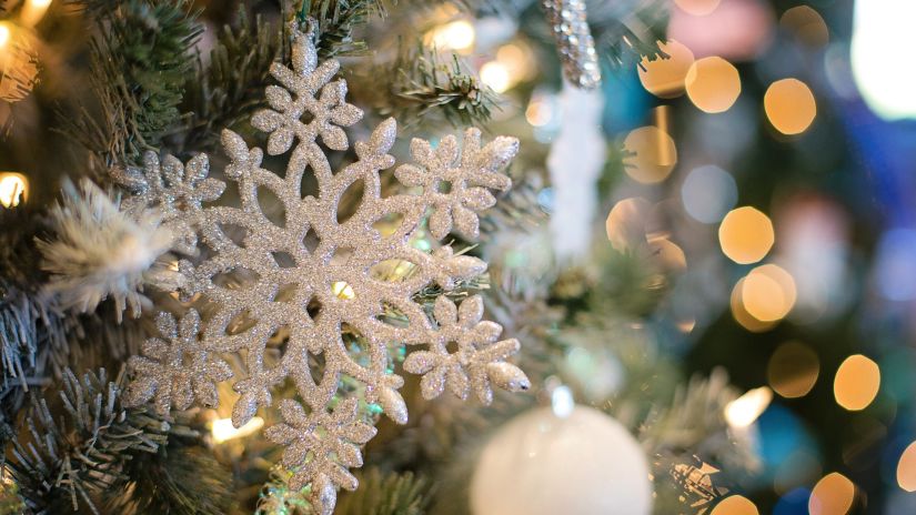 a close-up view of a christmas tree with snowflake shaped ornament hanging from it