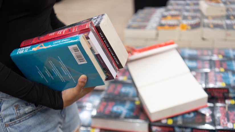 a girl holding books in her hand and reading one more with her other hand