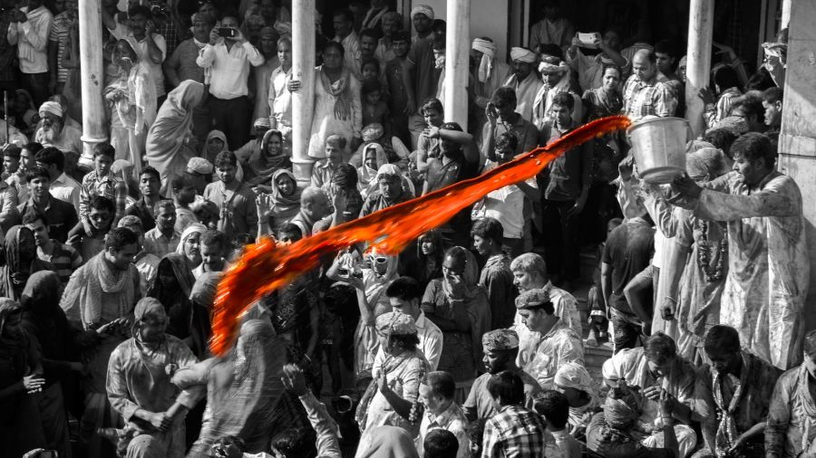 man throws colour at devotees at temple