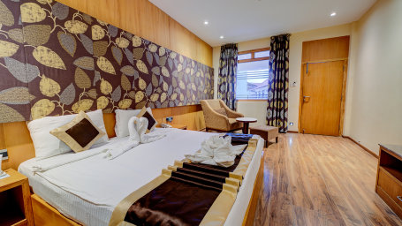 Cozy, king-sized bed in the Luxury Room, with a chair in the corner at Silver Sand Sentinel, Port Blair