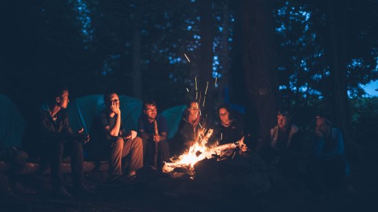 people sitting around a bonfire at night