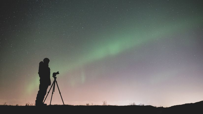 A person standing under the sky with a telscope, stargazing