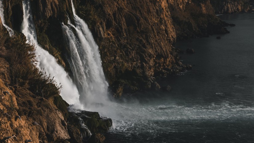 Waterfalls cascading from a cliff and joining a water body