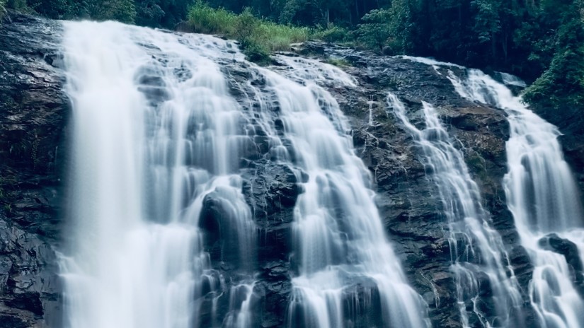 view of a gushing waterfall in Coorg surrounded with lush greenery