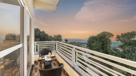 a balcony with two chairs and a table kept in the centre with mountain views - Stone Wood Mountain Resort, Dharamshala