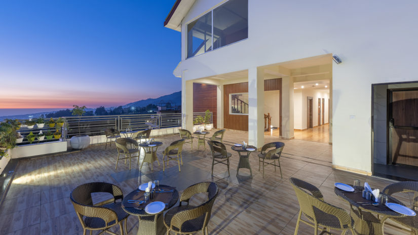 outdoor seating on a patio/terrace with different hues in the sky after a sunset - Stone Wood Mountain Resort, Dharamshala