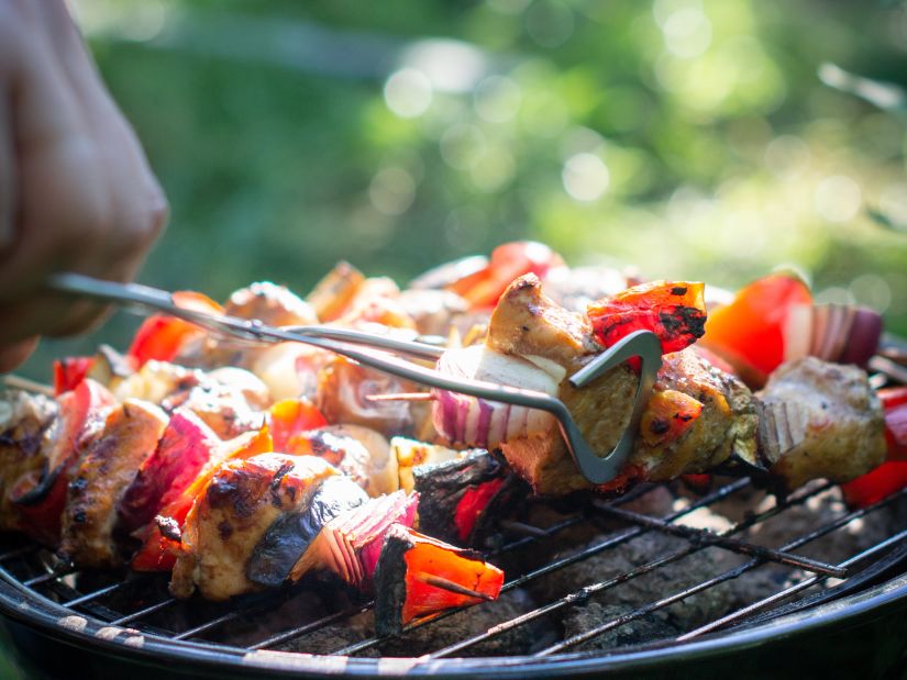 a person grilling skewered meat as an item at our buffet restaurant near Delhi