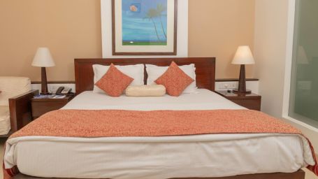 The king size bed in the premier room with peach coloured blanket at Kyriad Prestige Calangute, Goa