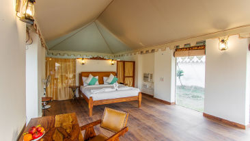 The interiors of the luxury tents at Sultan-e-Jawai featuring a comfortable bed, a table and chair, tasteful decor 