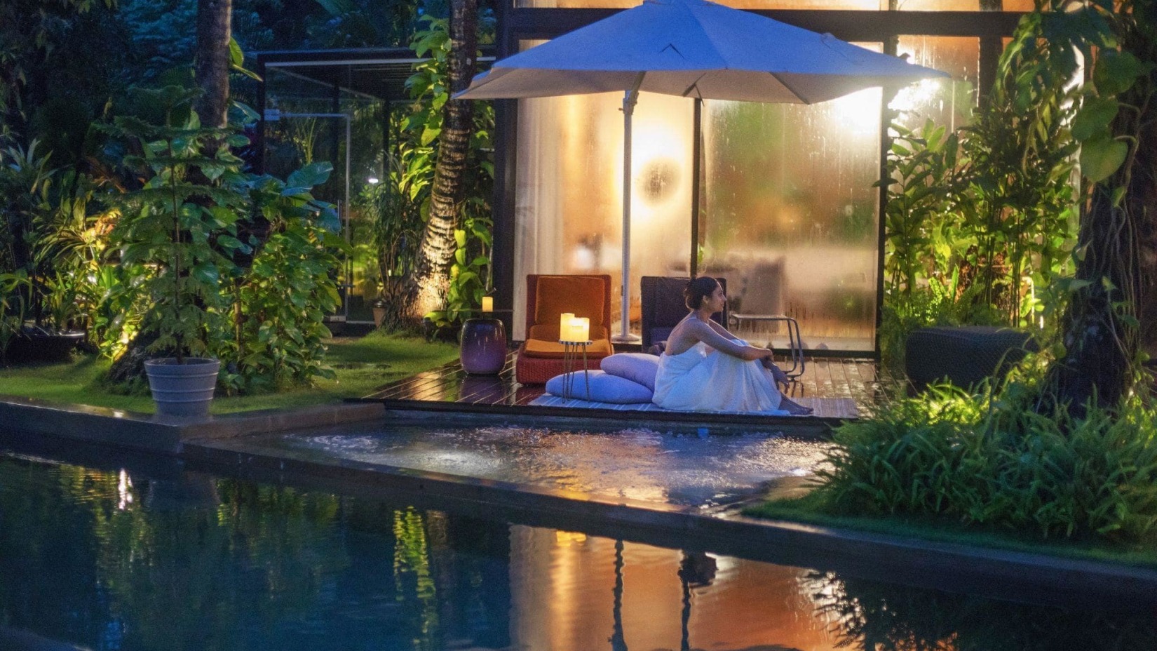 A woman rests near the pool adjacent to the hotel - Villa in Palms by V Escapes