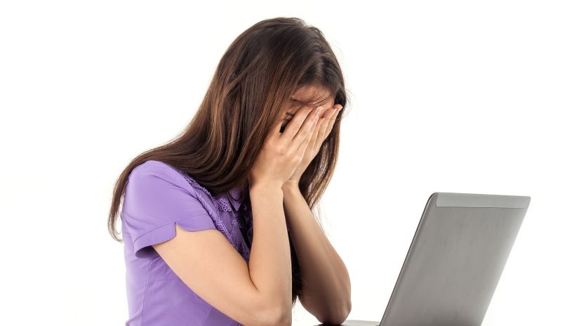 a young woman suffering from headache in front of her laptop